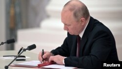 Президент Владимир Путин Ресей мен Украинаның шығысындағы "ДХР" және "ЛХР" сепаратистік құрылымдары арасындағы достық пен ынтымақтастық қарым-қатынас туралы келісімге қол қойып отыр. Мәскеу, 21 ақпан 2022 жыл.